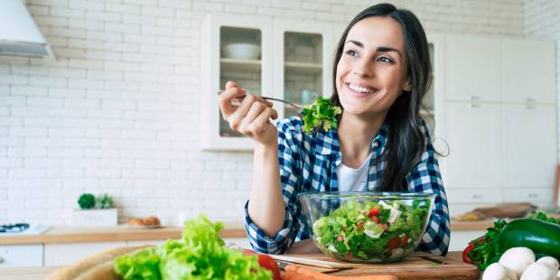 Healthy lifestyle. Good life. Organic food. Vegetables. Close up portrait of happy cute beautiful young woman while she try tasty vegan salad in the kitchen at home.
